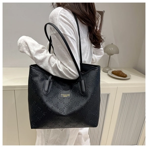 Detail of floral embossed texture and gold logo on large black leather tote bag