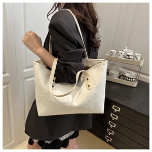 Detail of cream oversized tote bag with floral jacquard texture worn by model