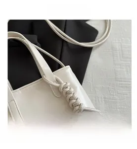 Détail du mini sac blanc avec un nœud tissé unique sur la poignée en cuir texturé