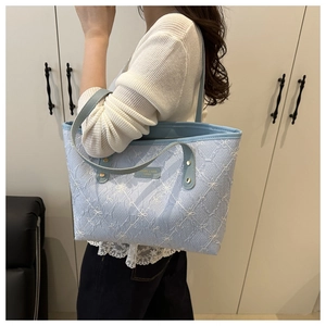 Detail of light blue tote bag featuring pleated texture and white bow embroidery accents