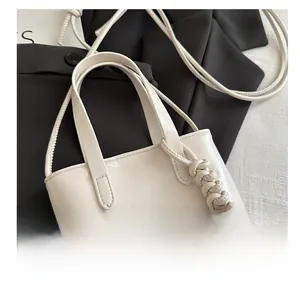 Gros plan d'un sac à main beige en cuir PU avec détail de nœud et poignée lisse