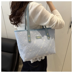 Detailed embroidery of small white bows on light blue striped tote bag with gold rivets