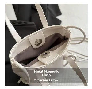 Vue macro d'un sac en cuir grainé blanc avec fermoir magnétique argenté et doublure grise