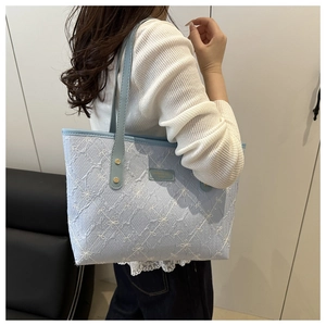 Close-up of light blue quilted tote bag with embroidery details and leather handles