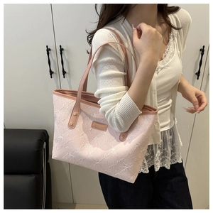 Detail view of pink tote bag with white floral embroidery and gold rivet accents