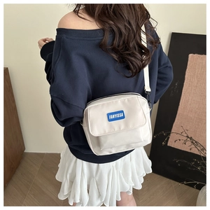 Close-up of a minimalist white crossbody bag with a blue FANYISSA brand label