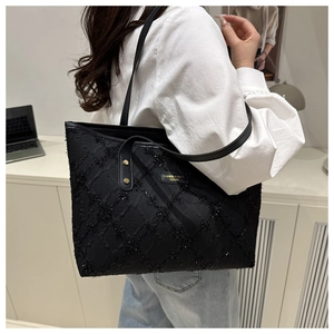 Detail of black tote bag with quilted 3D texture and branded fashion label