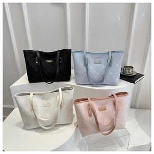 Close-up of four tote bags featuring floral embroidery, pastel colors, and gold rivet details