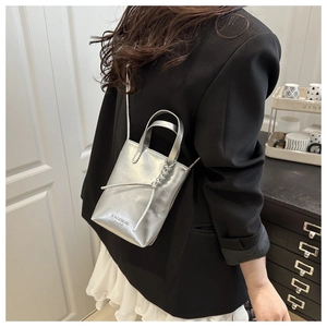 Silver metallic mini bag with 'FASHION BAGS' text and side knot detail worn cross-body