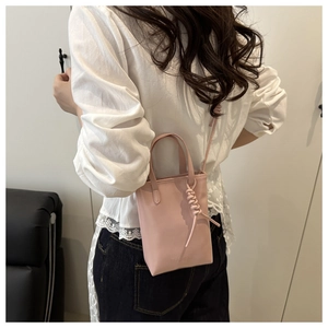 Dettaglio della mini borsa tote rosa con ciondolo intrecciato e testo fashion sul modello