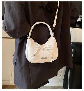 Gros plan d'un sac demi-lune blanc avec nœud décoratif, texture plissée et logo argenté