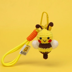 Macro detail of handmade crochet bee keychain with yellow texture and branded woven label