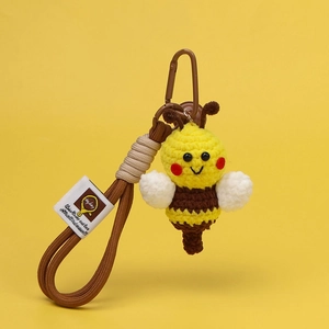 Close-up of handmade crochet bee keychain with yellow texture and brown carabiner clip