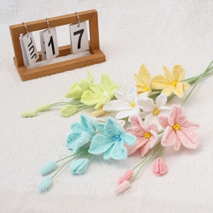 Handmade crochet lily flowers in pastel colors on a white textured tablecloth