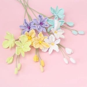 Handmade crochet orchid flowers in pastel colors with green stems on pink background