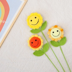 Trois tournesols au crochet faits main avec visages souriants sur un tissu texturé