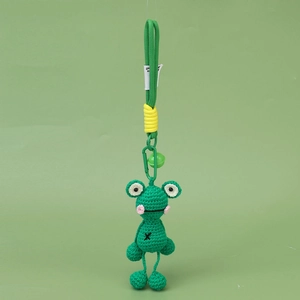 Nahaufnahme von handgefertigtem grünen Häkelfrosch-Anhänger mit Metallhaken und Glöckchen