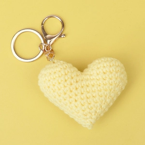 Close-up of a handmade yellow crochet heart keychain with a golden metal clasp