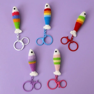 Detail of five handmade crochet rainbow fish keychains with colorful lobster clasps