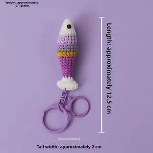 Detail view of a handmade crochet fish keychain in purple stripes with a metal carabiner