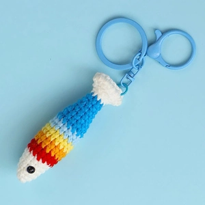 Close-up of handmade crochet rainbow fish keychain with blue plastic lobster clasp