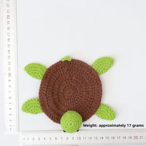 Flat lay of handmade crochet turtle coaster with measurement rulers on white background
