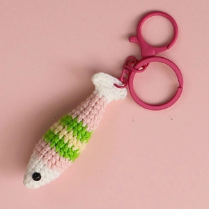 Handmade crochet colorful fish keychain with pink lobster clasp on soft pink background