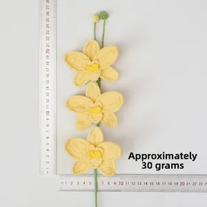 Macro view of handmade crochet yellow orchids showing size measurement with a ruler