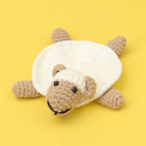 Detail of handmade crocheted sheep coaster with intricate textured white and brown yarn