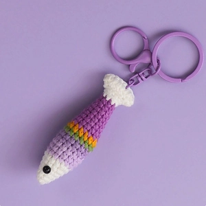 Handmade crochet fish keychain with purple yarn and colorful stripes on soft background