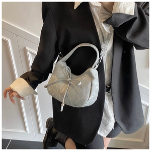 Détail du sac à main gris effet froissé avec nœud décoratif et logo métallique chic
