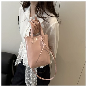 Dettaglio borsa in pelle rosa lucida con tracolla annodata e logo FASHION BAGS inciso