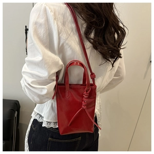 Dettaglio della borsa rossa in pelle con nodo decorativo e scritta Fashion sulla base