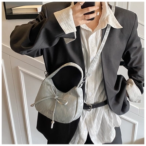 Détail du sac croissant gris avec nœud décoratif et cuir plissé aux reflets brillants