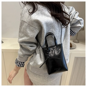 Close-up of a mini black glossy shoulder bag with Fashion Bags text and dual handles