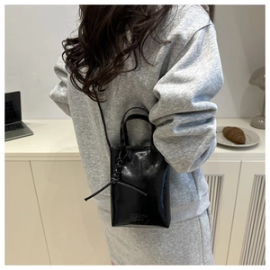 Vue latérale du sac seau noir brillant avec détail de nœud et lettrage FASHION