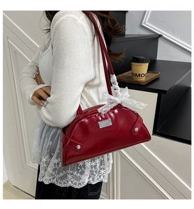 Detail of red patent leather shoulder bag with white lace bow and metal logo plate