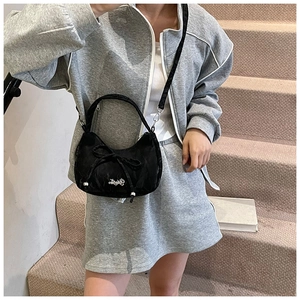Détail du sac hobo noir avec nœud en nylon porté par un mannequin pour un style quotidien