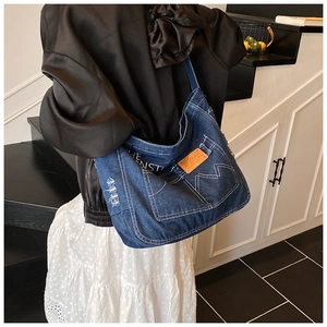 Close-up of vintage blue denim tote bag featuring white contrast stitching and a leather tag