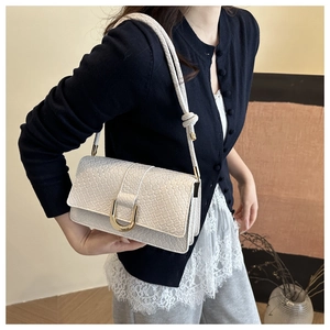 Detailed view of cream crocodile textured shoulder bag with gold U-shaped metal clasp