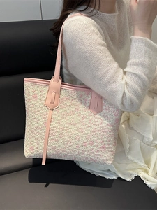 Rosa-beige geflochtene Tragetasche mit Ledergriffen an einem Modell für einen Casual-Look