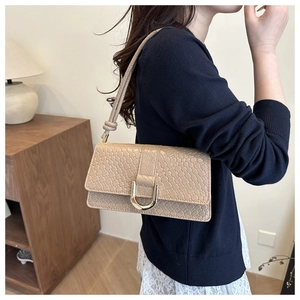 Detail of beige embossed leather shoulder bag with elegant golden U-shaped buckle