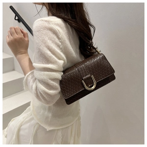 Close-up of a brown crocodile pattern shoulder bag with a gold U-shaped metal buckle