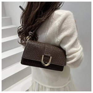Detail of dark brown faux crocodile leather bag with gold U-shaped magnetic clasp
