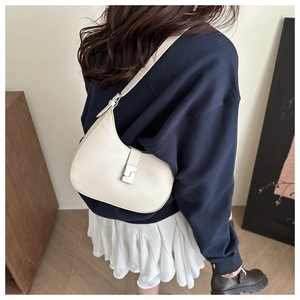 Detailaufnahme einer cremefarbenen Halbmodtasche aus Leder mit silberner Schnalle am Model