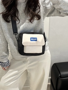 Minimalist black and white messenger bag with adjustable nylon strap and blue woven label
