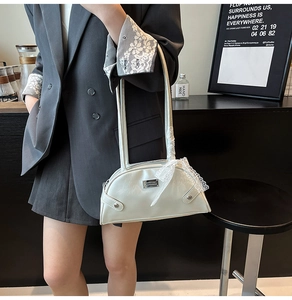Detail of off-white PU shoulder bag featuring lace-wrapped handle and metal brand plaque