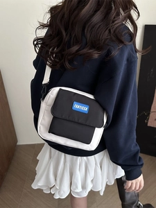 Minimalist black and white messenger bag with blue logo patch and adjustable strap