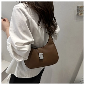 Detail einer braunen Hobo-Tasche aus Leder mit silberner Schnalle und dünnem Riemen