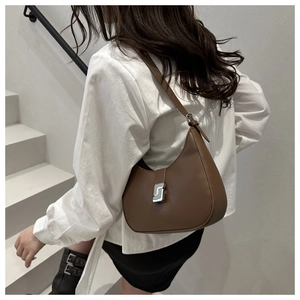 Braune Halbmond-Ledertasche mit S-Verschluss, getragen von einem Modell auf Treppen